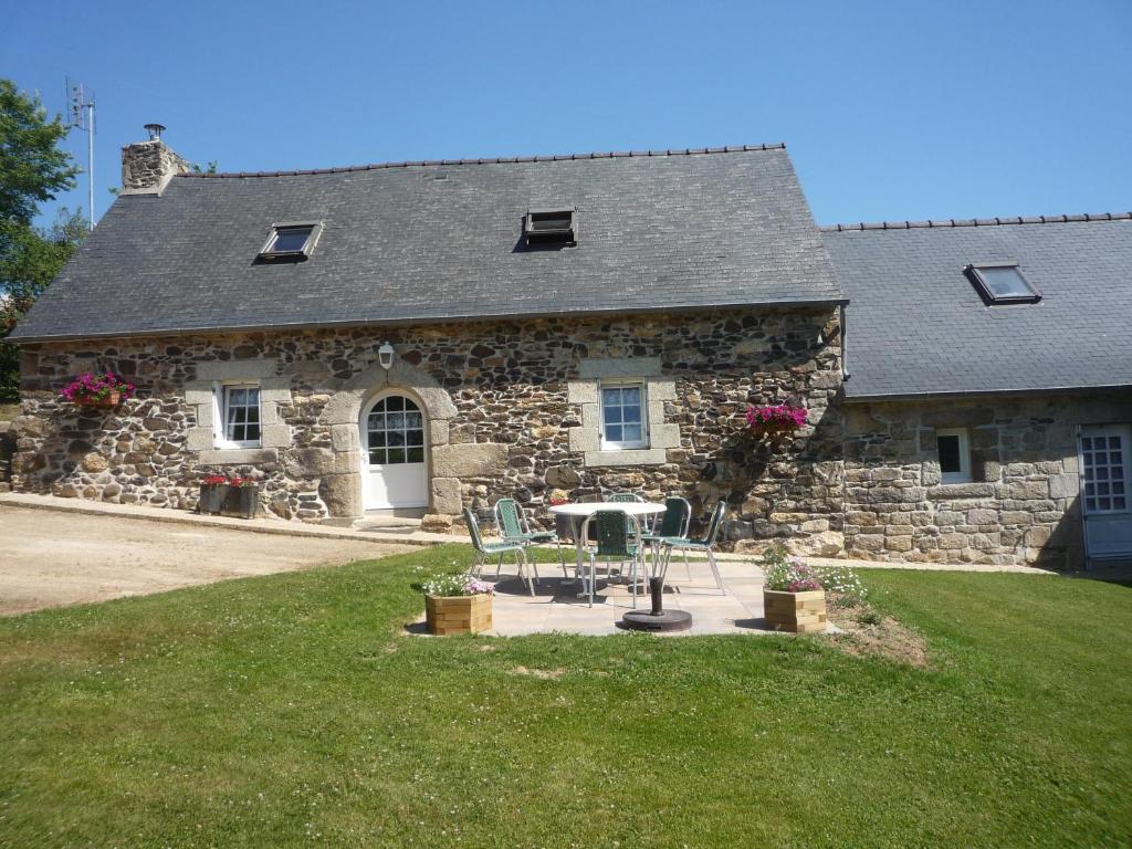 uma casa de pedra com uma mesa e cadeiras em frente em LES BRUYERES em Scrignac