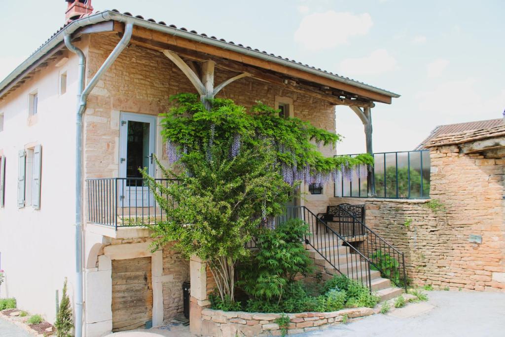 une maison en briques avec un arbre devant elle dans l'établissement LE CLOS DES PIERRES ROUGES, à Burgy