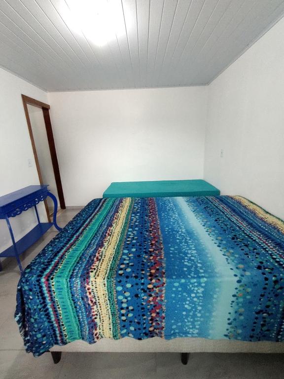 a bedroom with a bed with a colorful blanket on it at Apartamento em chácara próximo as praias com piscina e quiosque com internet in São Francisco do Sul