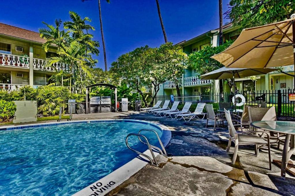a swimming pool with chairs and tables and an umbrella at NAUTICAL THEME GARDEN VIEW STUDIO - KONA ISLANDER INN CONDOS condo in Kailua-Kona