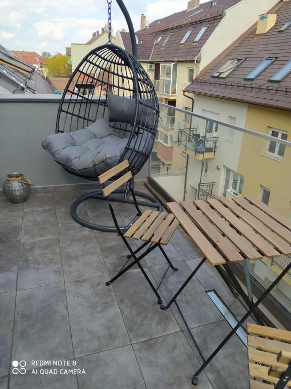 a swing and a bench on a balcony at Modern Apartman in Szeged