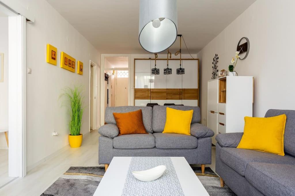 een woonkamer met een grijze bank en gele kussens bij Flat White Apartment in Boedapest