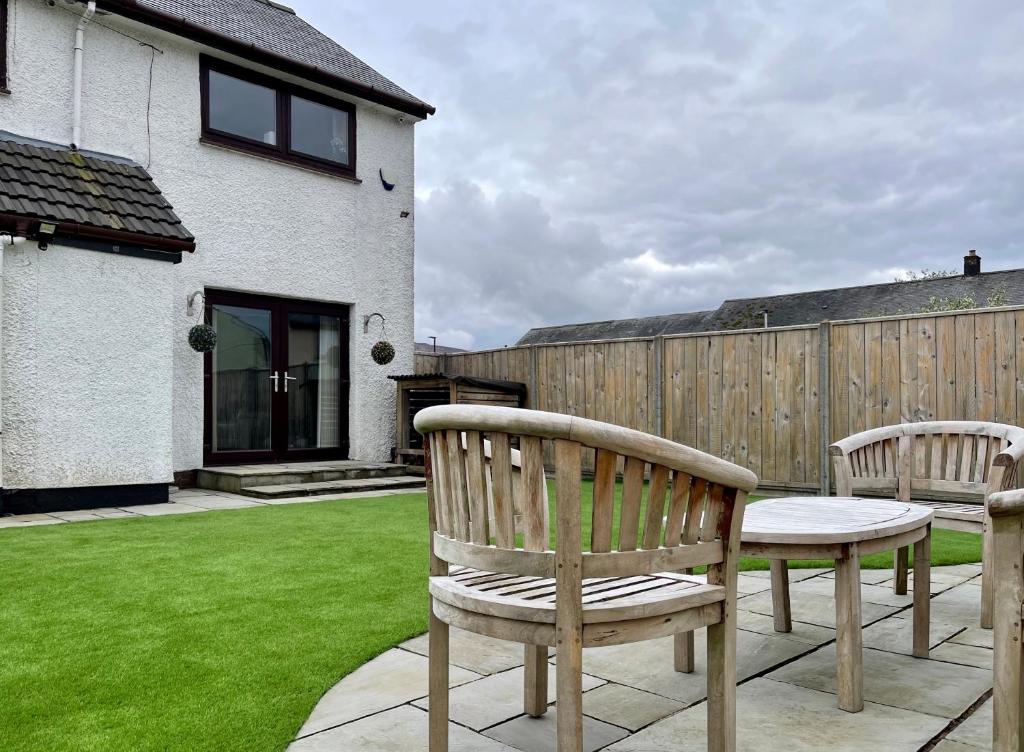 two wooden chairs and a table in a yard at Feel at home while you roam in Caol