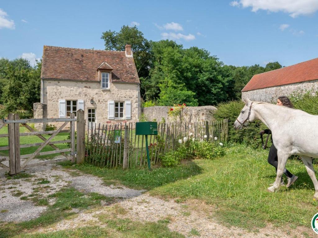 a horse walking in front of a house at Gîte Montépilloy, 3 pièces, 4 personnes - FR-1-526-30 in Montépilloy