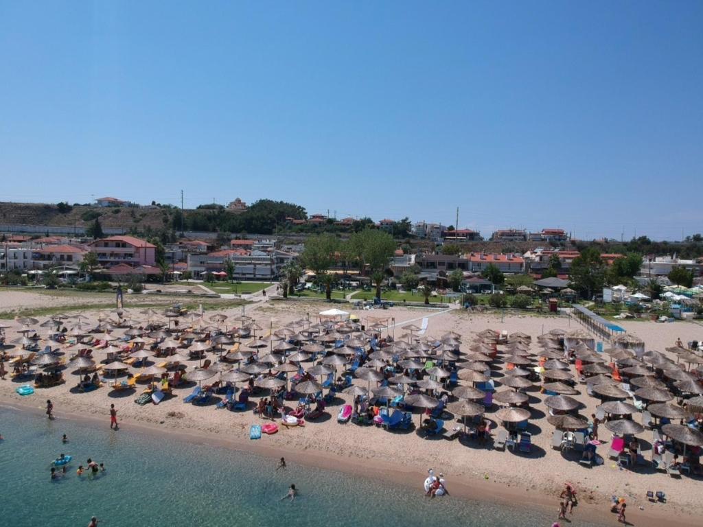 a beach with many umbrellas and people in the water at Prassas Sea View in Nea Potidaea