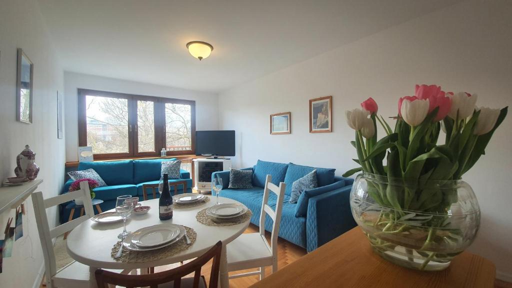 a living room with a table and a vase of flowers at JLS Apartament z parkingiem przy plaży in Gdańsk