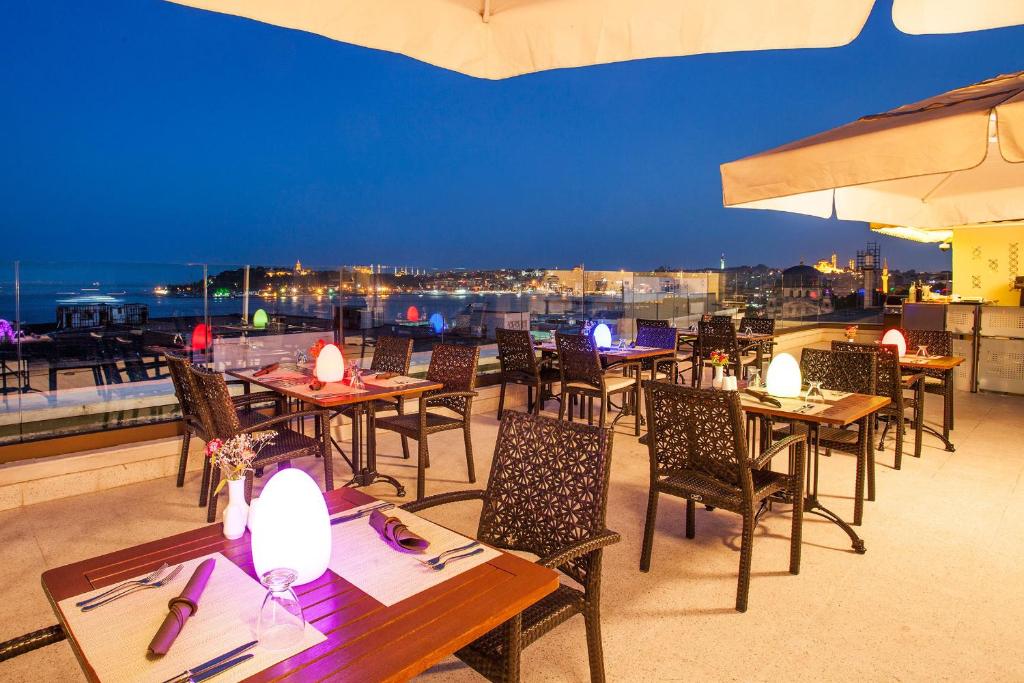 a restaurant with tables and chairs on a roof at Nidya Hotel Galataport in Istanbul