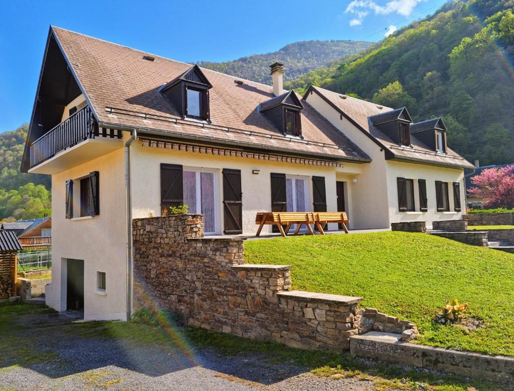 una casa en una colina con una pared de piedra en Grande villa avec jardin privatif - Bagnères de Luchon en Juzet-de-Luchon