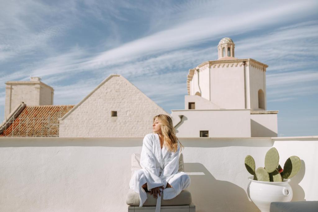 a woman sitting on a wall in front of a building at Dimora Anderì in Polignano a Mare