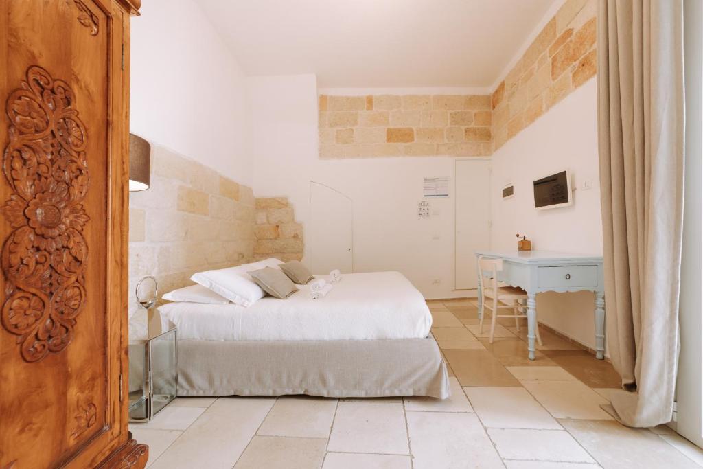 a white bedroom with a bed and a desk at Dimora Anderì in Polignano a Mare