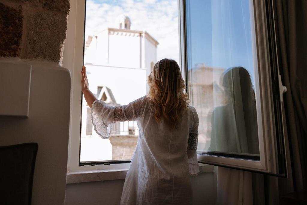 a woman is looking out of a window at Dimora Anderì in Polignano a Mare