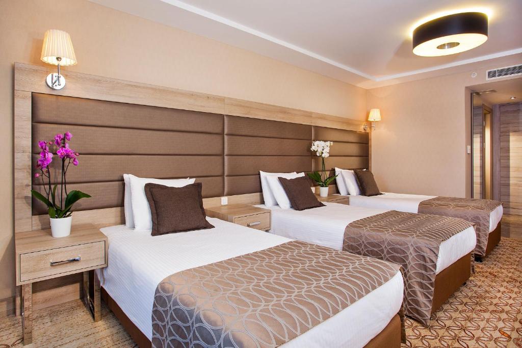 a hotel room with three beds and flowers in it at Nidya Hotel Galataport in Istanbul