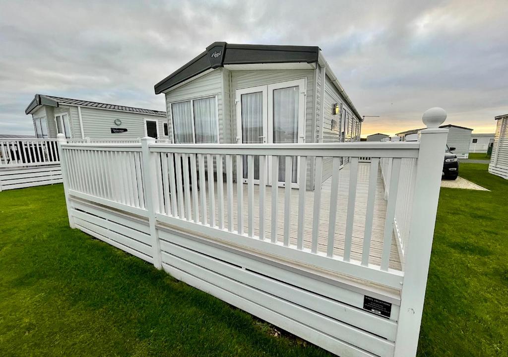 a white picket fence with a house behind it at Luxury 3 bedroom caravan between Perranporth and Newquay, Cornwall in Newquay