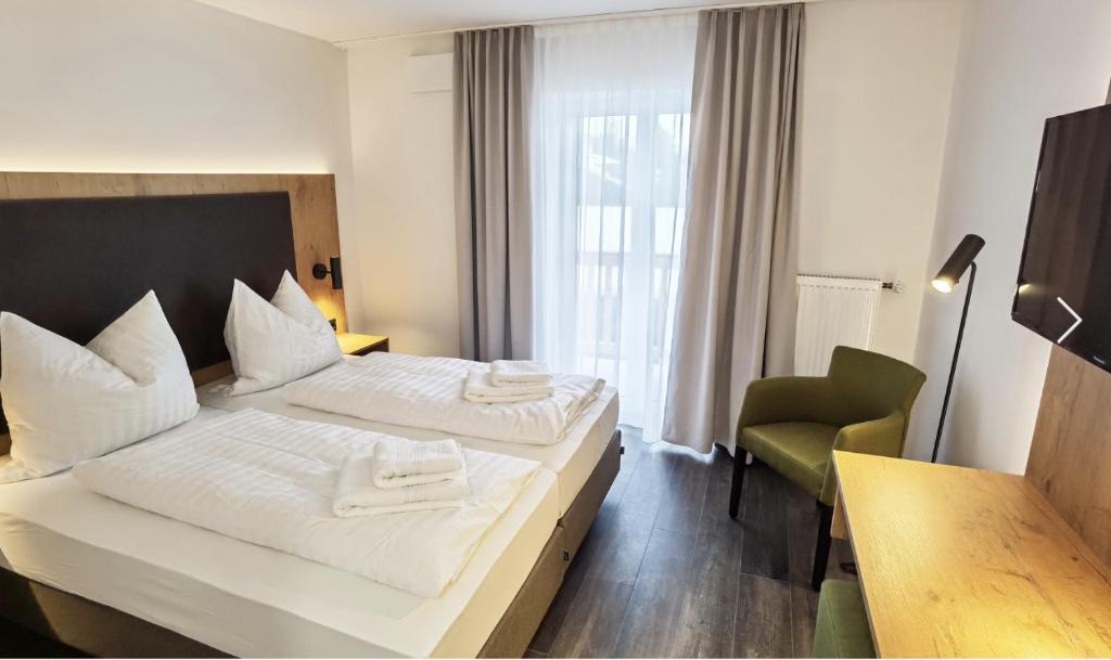 ein Hotelzimmer mit zwei Betten und einem Stuhl in der Unterkunft Waldschlößl in Bruckmühl