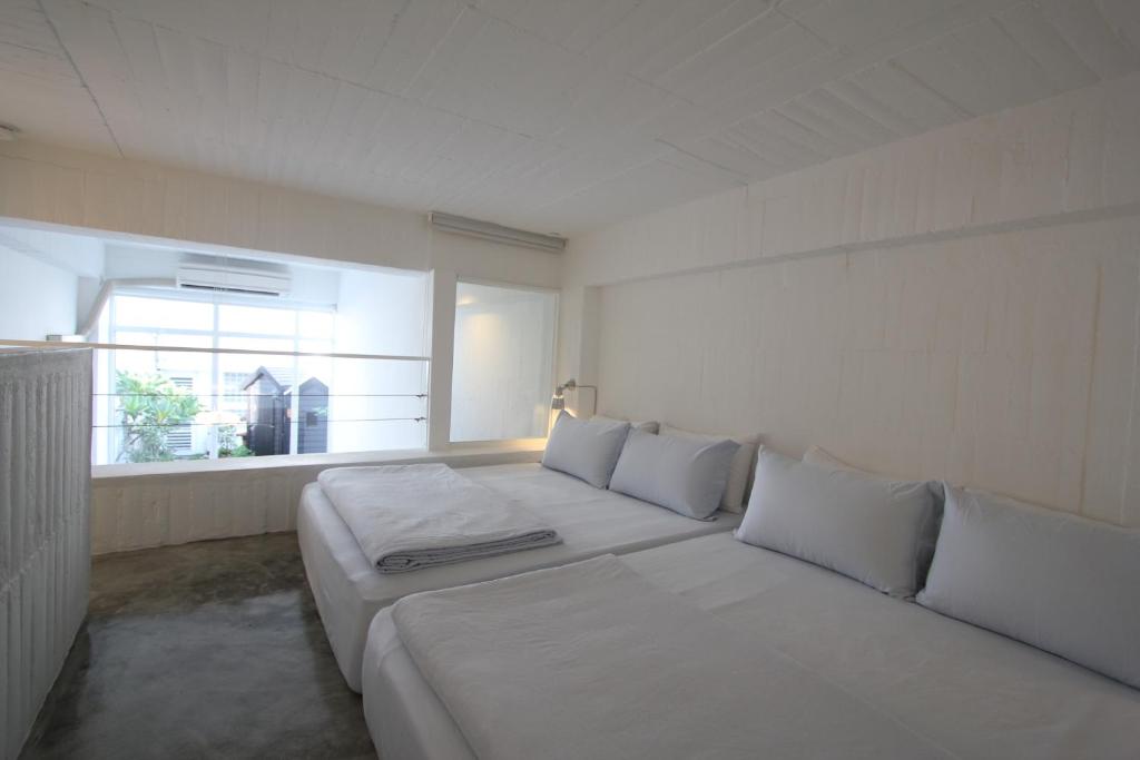 a white room with two beds and a window at Milk White Homestay in Hengchun South Gate