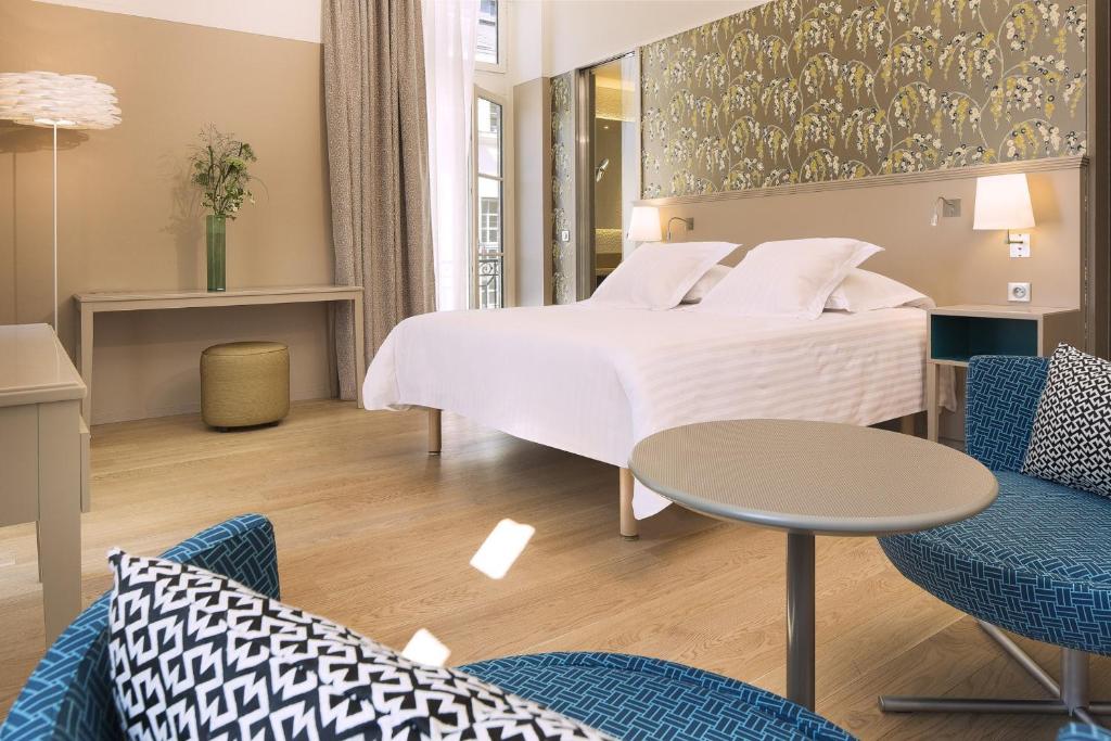 une chambre d'hôtel avec un lit, une table et des chaises dans l'établissement Oceania l'Hôtel de France Nantes, à Nantes