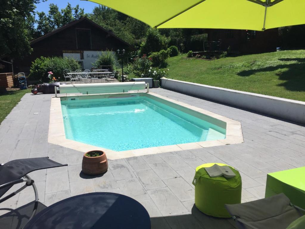 una piscina en un patio con sombrilla en MORTZI villa 4 étoiles avec piscine en Mortzwiller