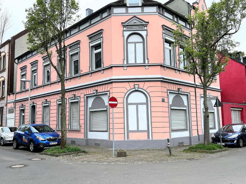 un bâtiment rose avec une voiture bleue garée devant. dans l'établissement Wohnung in Düren Stadtmitte, à Düren