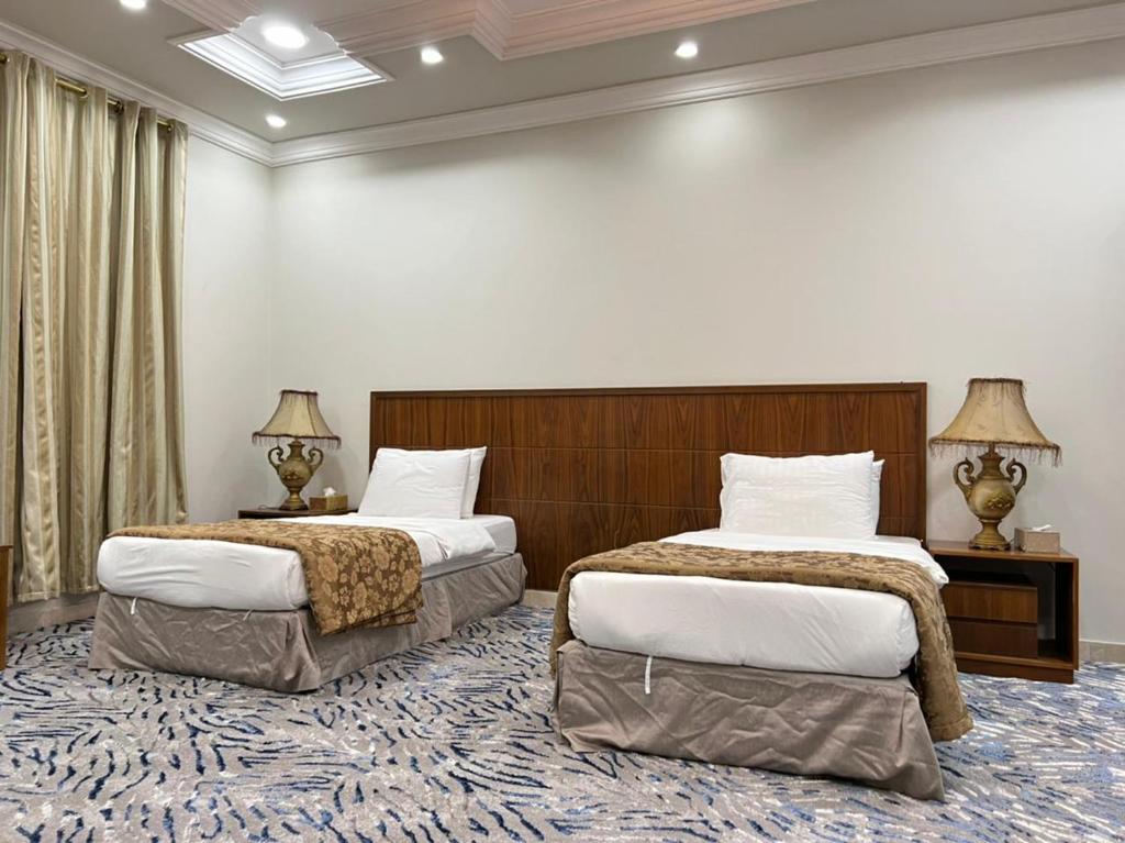 a hotel room with two beds and two lamps at سويت ان العلا للشقق المفروشة الخاصة Sweet In alula Apartments and organizing tours in Al-ʿUla