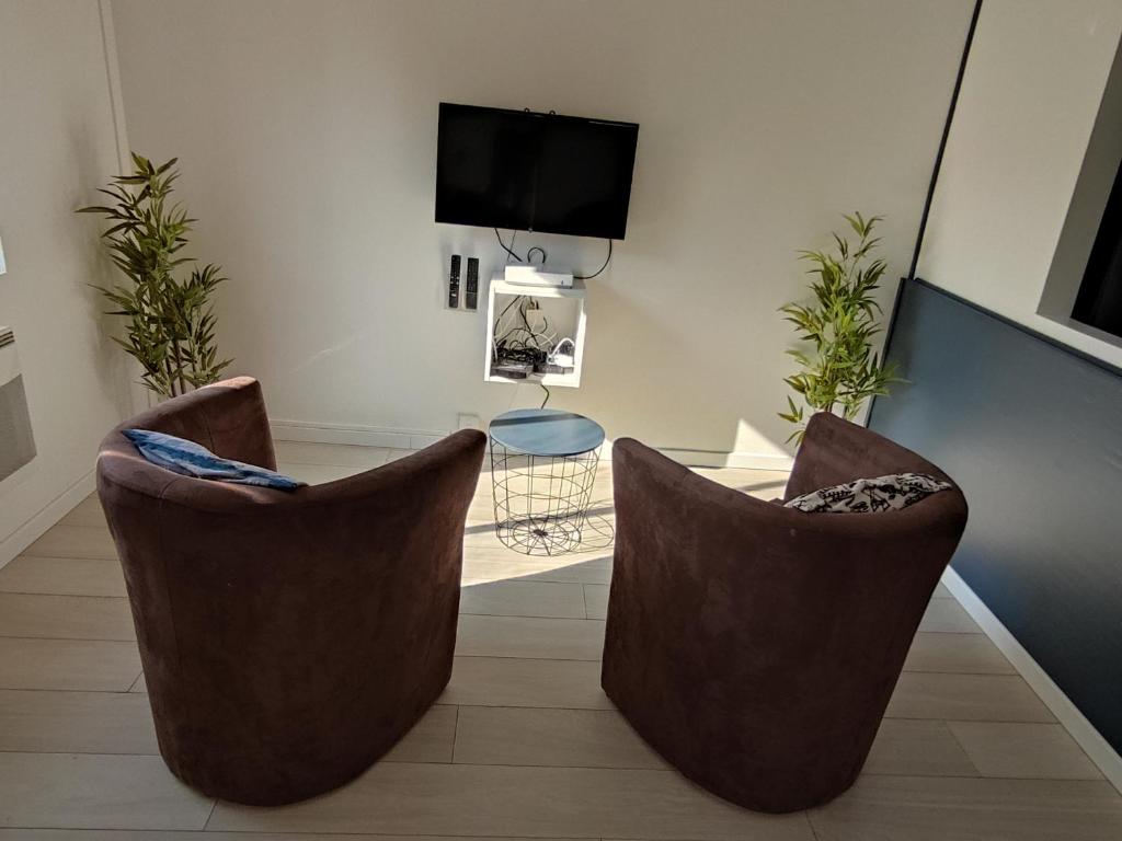 uma sala de estar com duas cadeiras castanhas e uma televisão em Résidence Les Hauts de France em Noeux-les-Mines