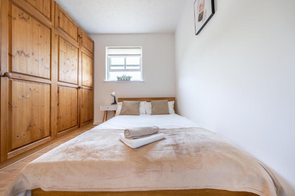 a bedroom with a large bed with wooden cabinets at Stansted Airport & Bishops Stortford Town Centre Professional Apartment in Bishops Stortford