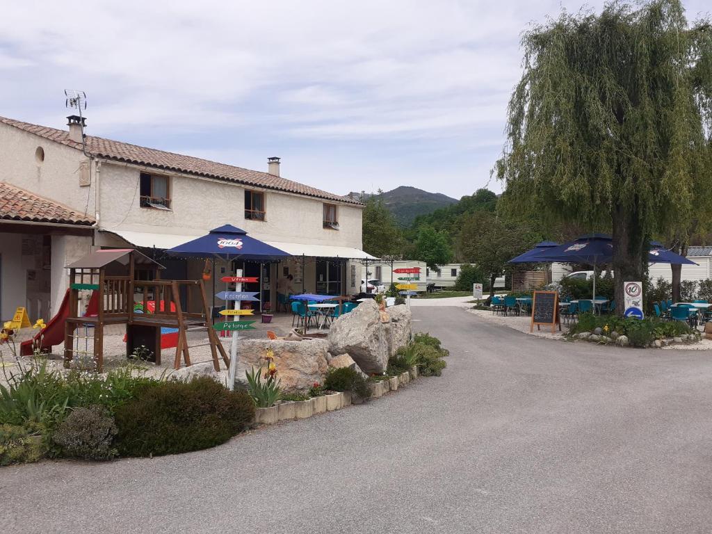 a building with tables and umbrellas on a street at Camping les Lavandes, Castellane in Castellane