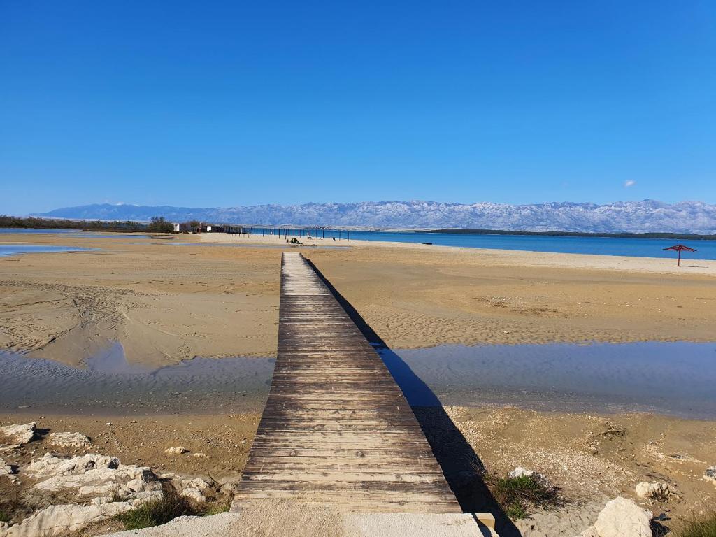 a wooden boardwalk stretches out into the water on a beach at Apartments Cesare in Nin