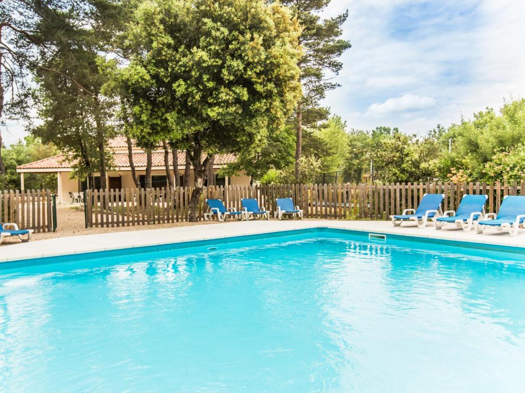 une piscine avec des chaises bleues et une clôture dans l'établissement Villa La Lauze, à Labastide-de-Virac