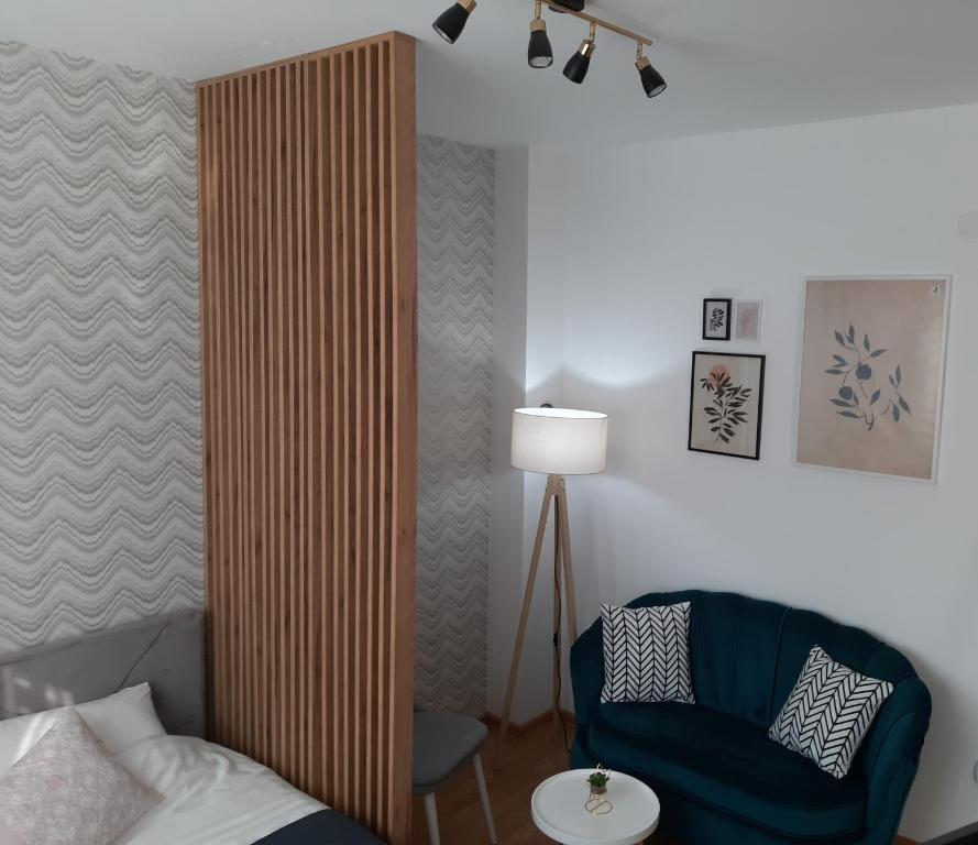Cette chambre comprend un lit, une chaise et une lampe. dans l'établissement Apartman Poco, à Bijeljina