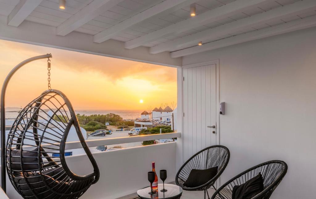 Sunset Windmills Suites في مدينة ميكونوس: غرفة بها كرسيين ونافذة مطلة على المحيط