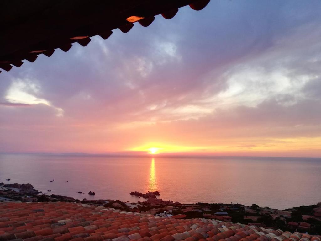 een zonsondergang boven het water met de zon in de lucht bij Una terrazza in Paradiso in Costa Paradiso