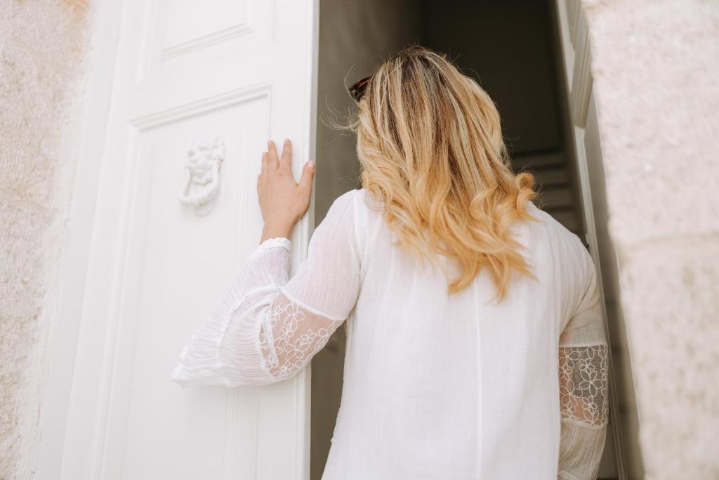a woman in a white shirt looking out of a door at Dimora Anderì in Polignano a Mare