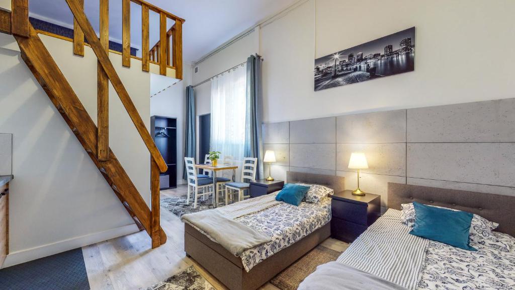 Habitación de hotel con 2 camas y escalera en City Place Noclegi, en Wroclaw
