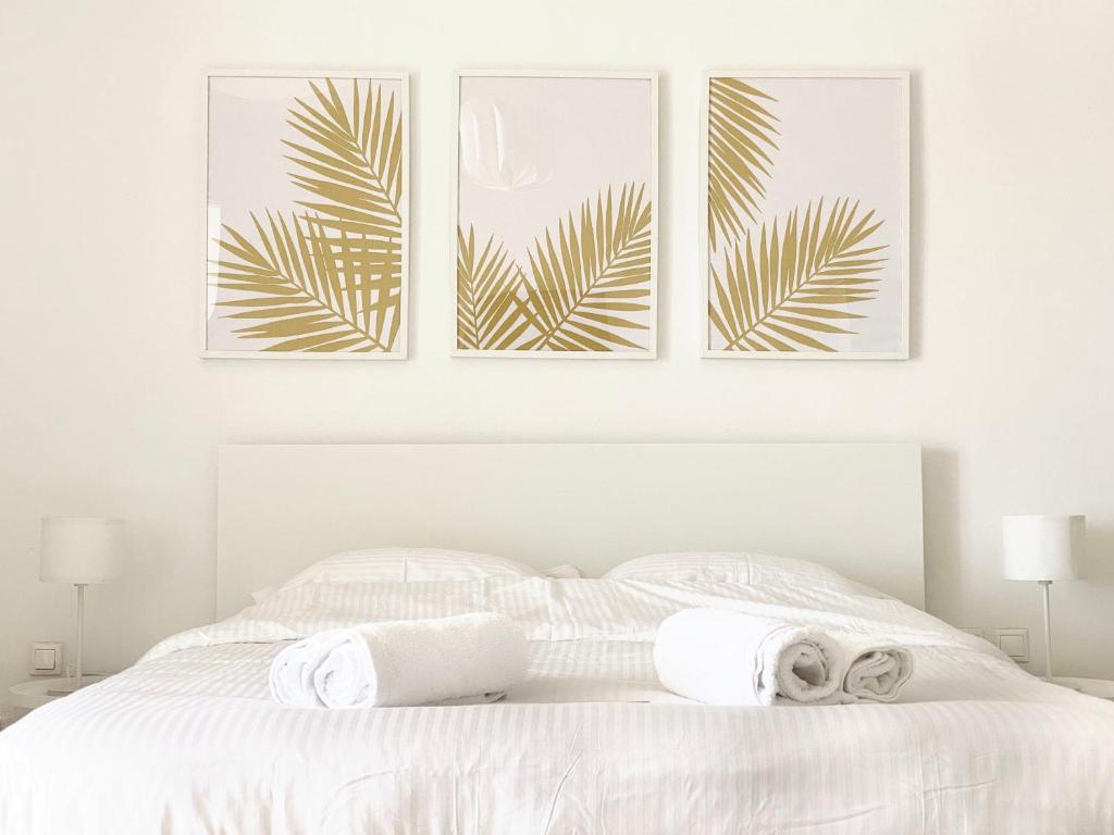 una camera da letto con un letto bianco con tre immagini sul muro di Palm Suite Yellow a Porto Heli