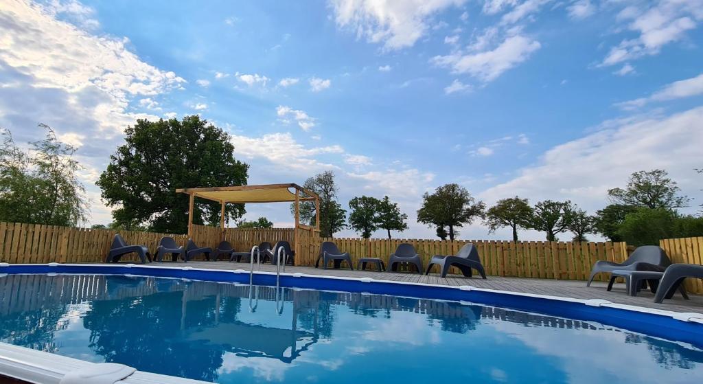 une piscine avec des chaises et un gazebo dans l'établissement Le Petit Moulin, à Saint-Hilaire