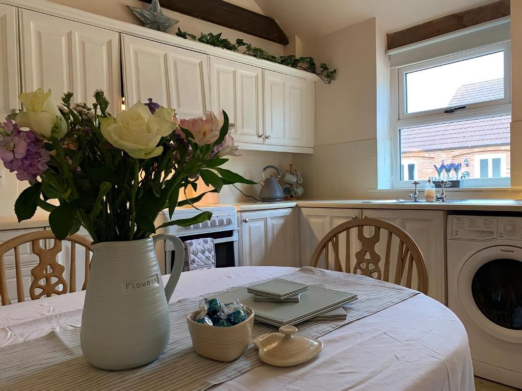 a white vase with flowers on a table in a kitchen at Hawthorn Cottage at Waingrove Farm in Fulstow