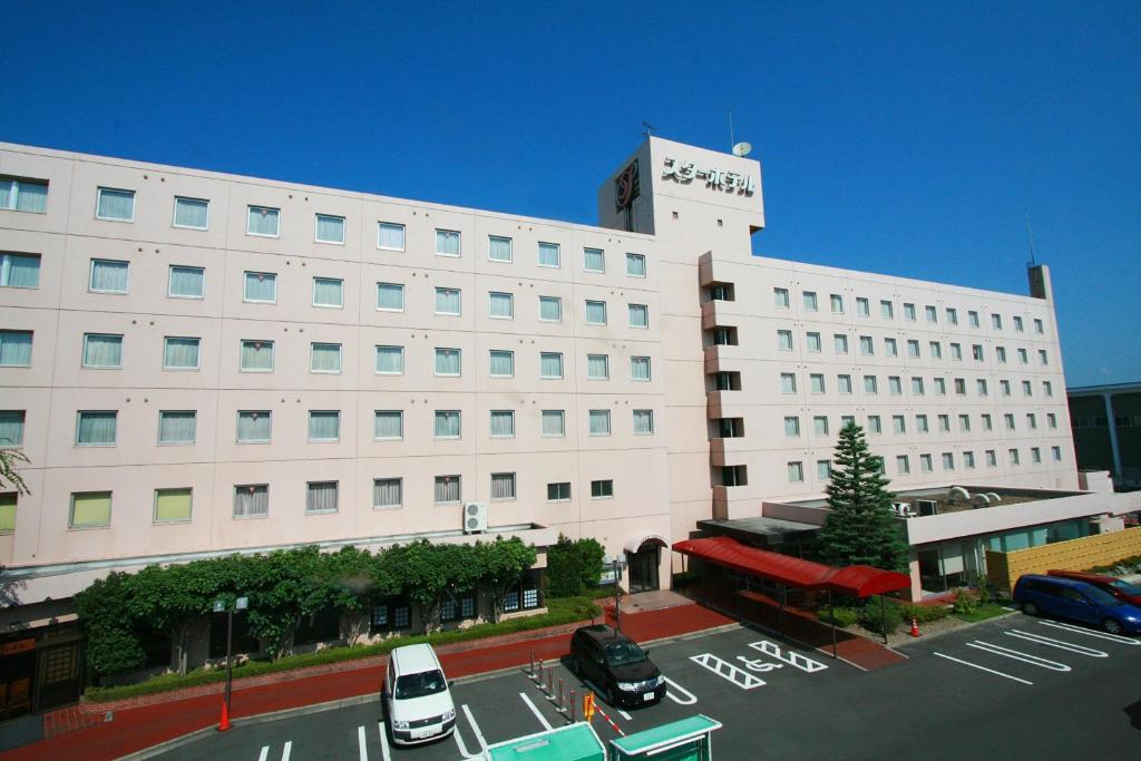 郡山市にあるスターホテル郡山の大きな白い建物と駐車場に駐車された車