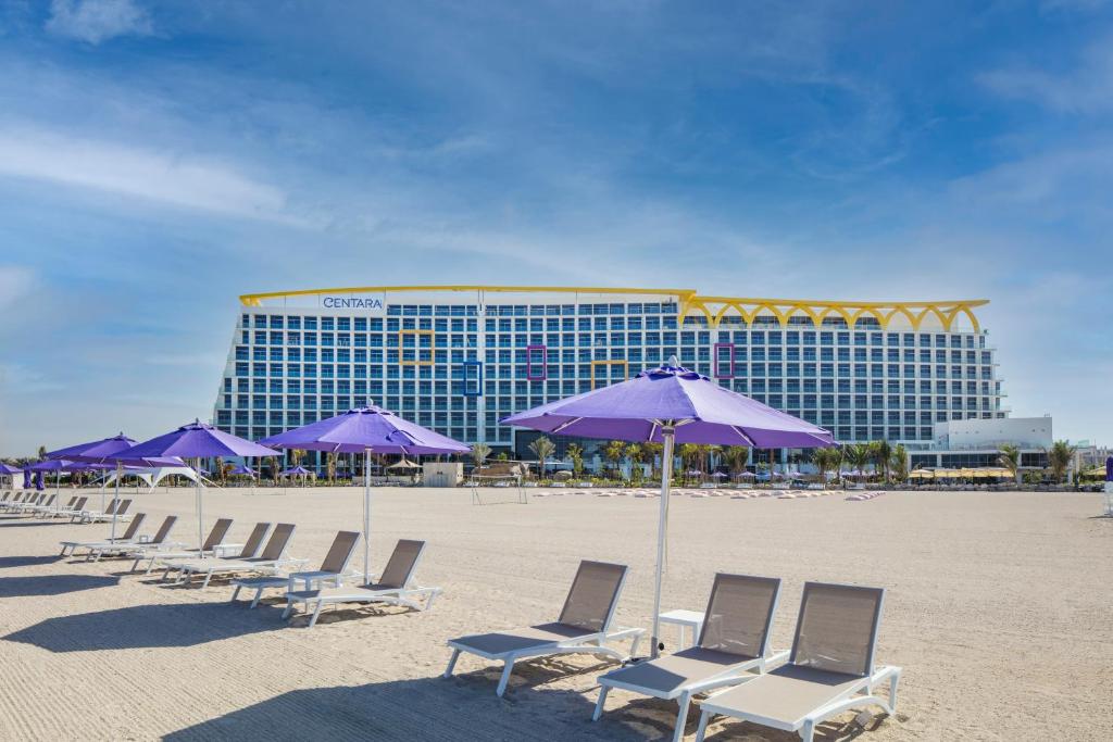 uma fila de cadeiras e guarda-sóis numa praia em Centara Mirage Beach Resort Dubai em Dubai
