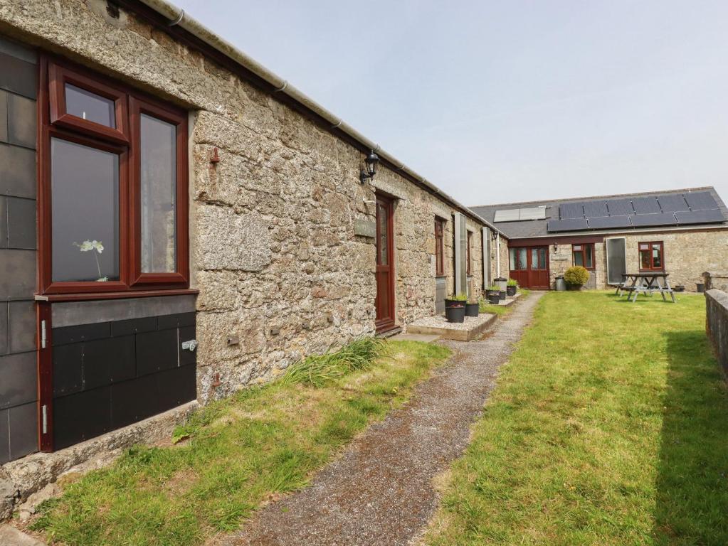 a stone building with a grass yard next to it at Badgers Sett in Lanivet