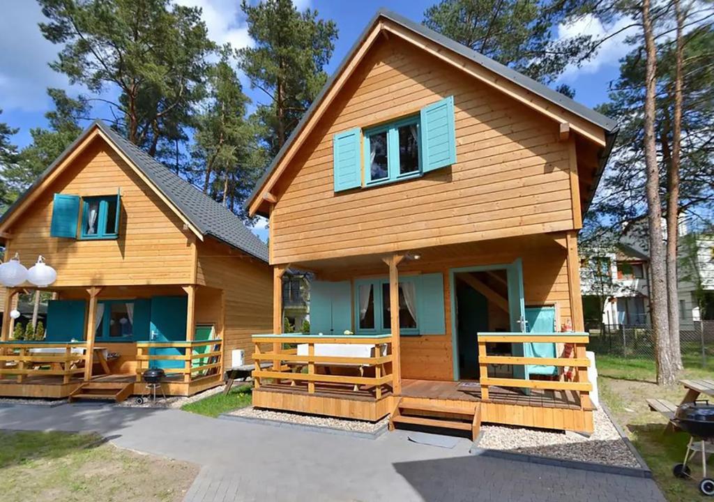 Cette maison en rondins est dotée de fenêtres bleues et d'une terrasse couverte. dans l'établissement Kolorowe Domki, à Pobierowo
