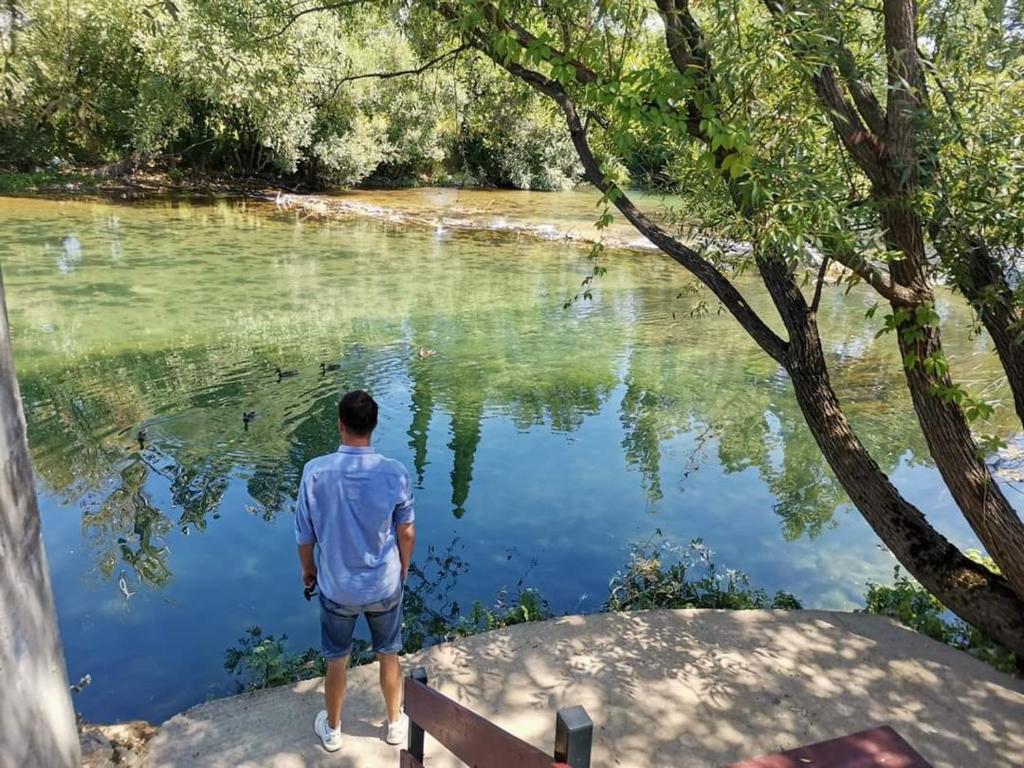 un hombre parado junto a un cuerpo de agua en RiverView Buna - Mostar, en Buna