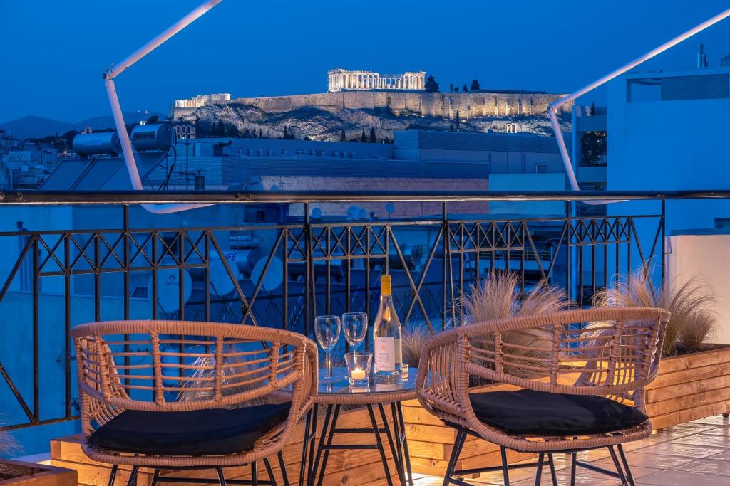 a table and chairs on a balcony with a bottle of wine at Parthenon Dream, breathtaking views with free parking in Athens