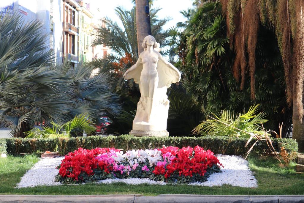 Una statua di un angelo in un giardino fiorito di kaDevi piazza Bresca - pieno centro, parcheggio, bici a Sanremo