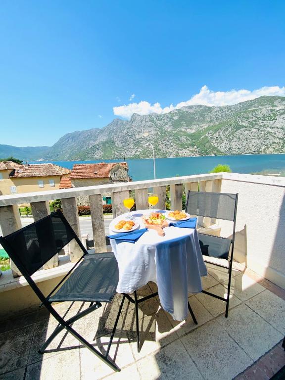 a table with two chairs and two glasses on a balcony at Villa Blanca in Risan