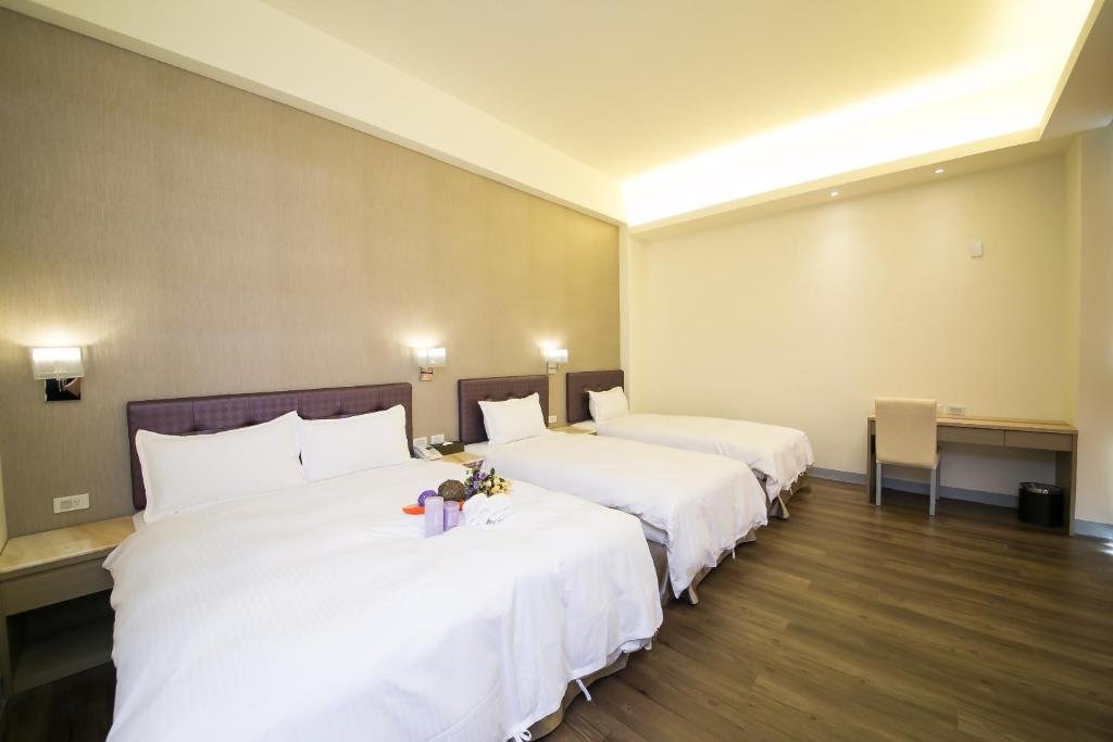 two beds in a hotel room with white sheets at Sunseed International Villa Hotel in Chiayi City