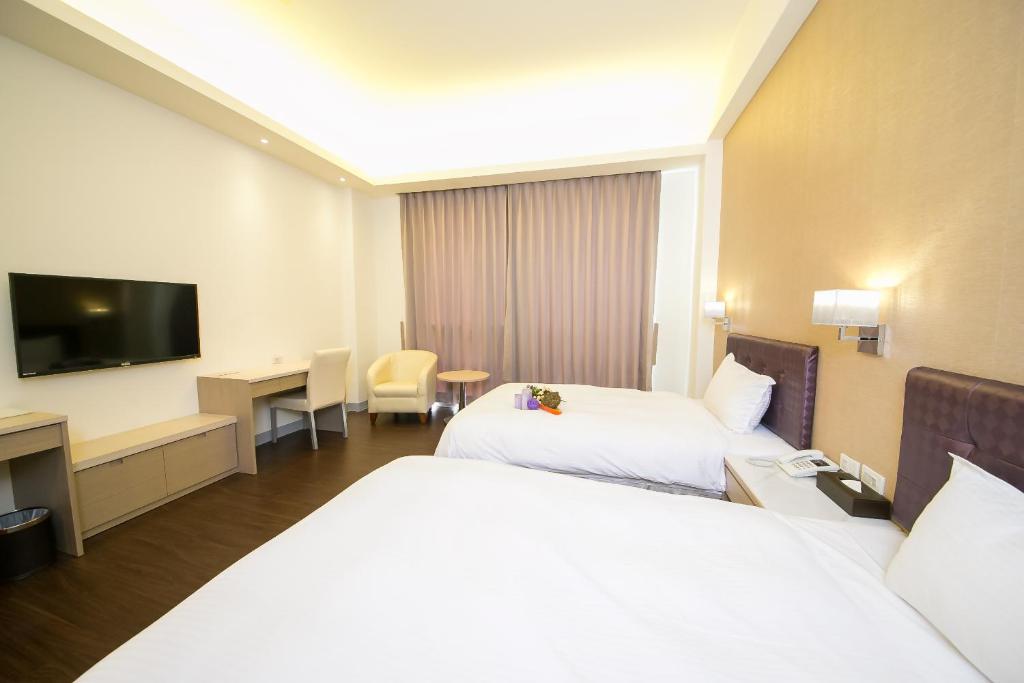 a hotel room with two beds and a flat screen tv at Sunseed International Villa Hotel in Chiayi City