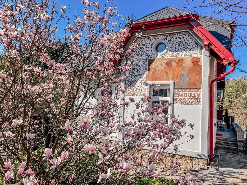 una casa con un árbol floreciente delante de ella en Villa Emausy en Luhačovice