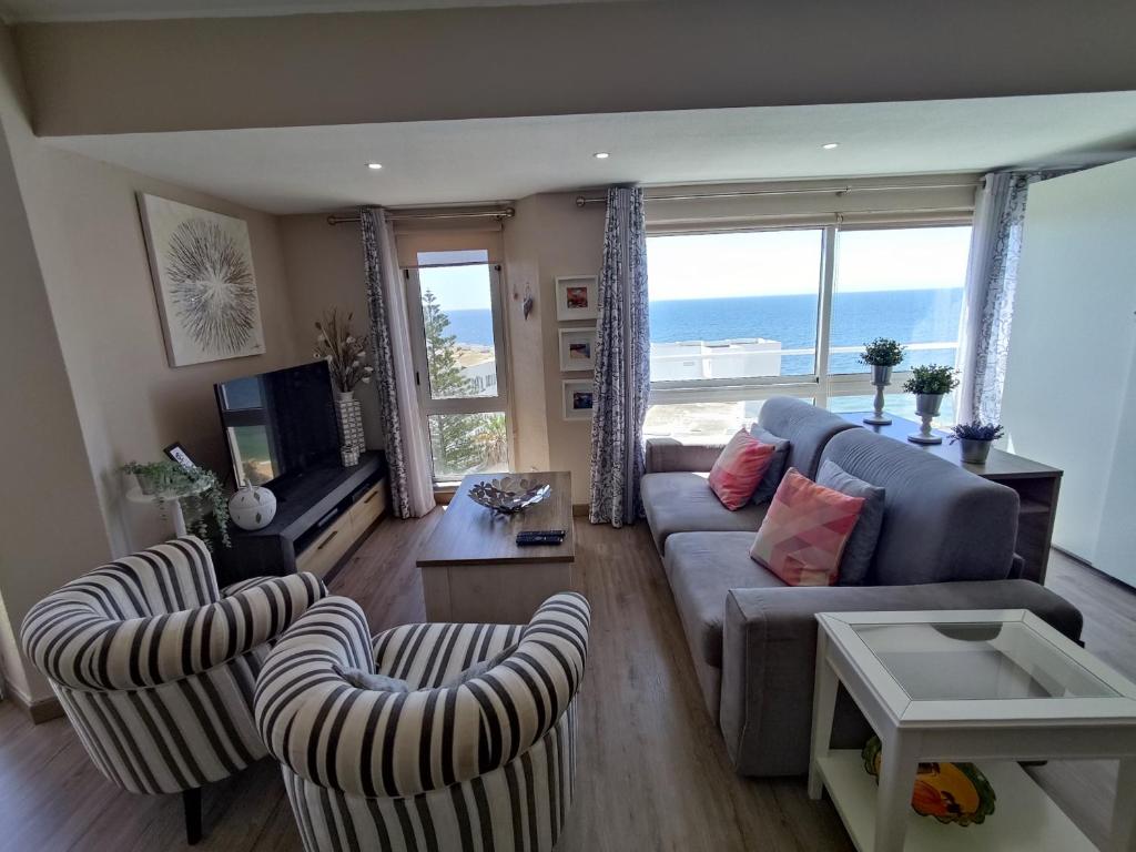 a living room with a couch and chairs and the ocean at 7C Invicta - Casas & Papeis in Armação de Pêra