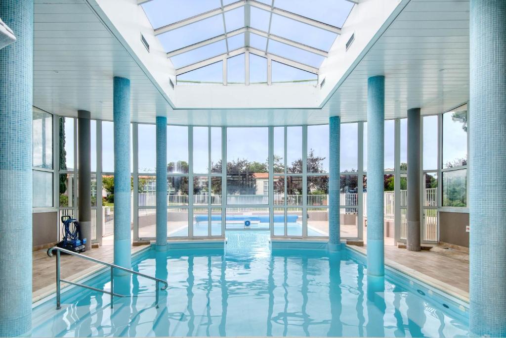 a large swimming pool with blue columns and windows at NATICE Bel appartement dans résidence privée in Saint-Martin-de-Ré