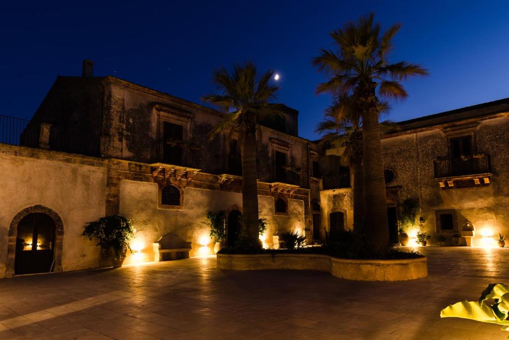 a building with palm trees and lights at night at Borgo del Carato in Solarino